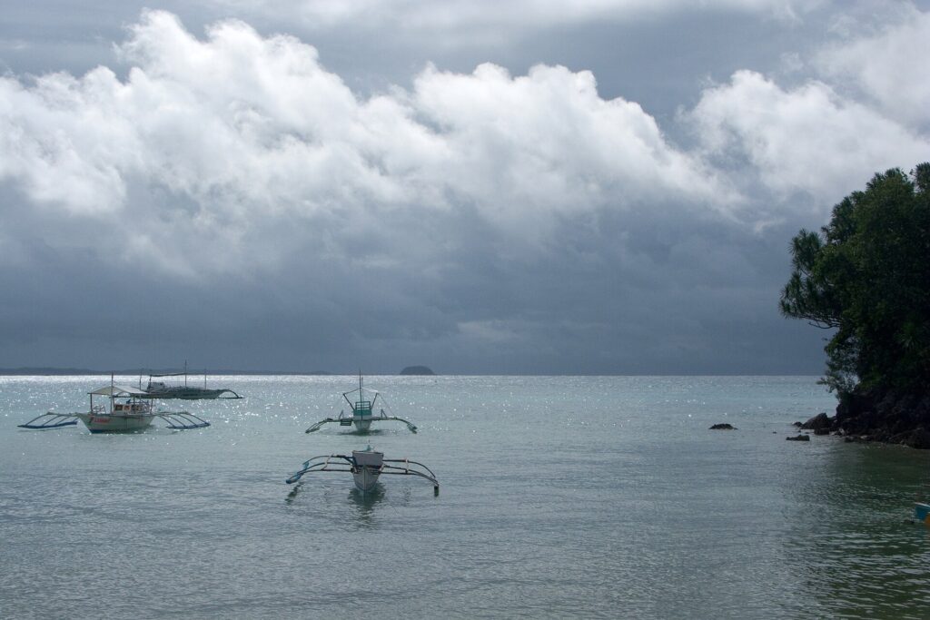 Bangka boats on grey-green water under dark clouds in the Visayan Sea