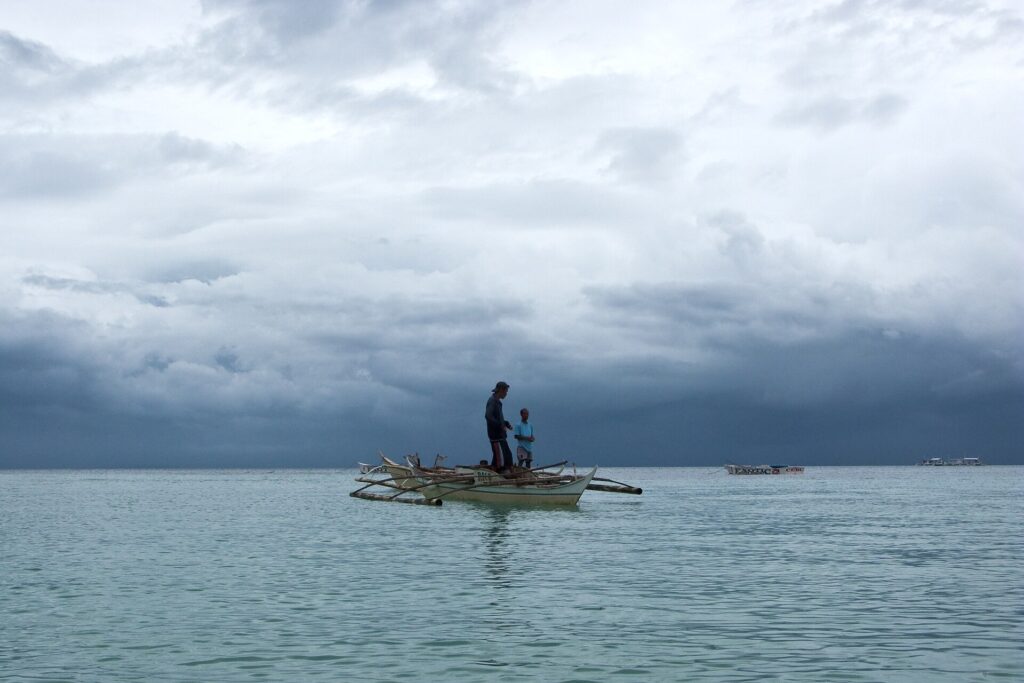 Heavy grey storm clouds over the calm Visayan Sea with a fisherman standing on a bangka