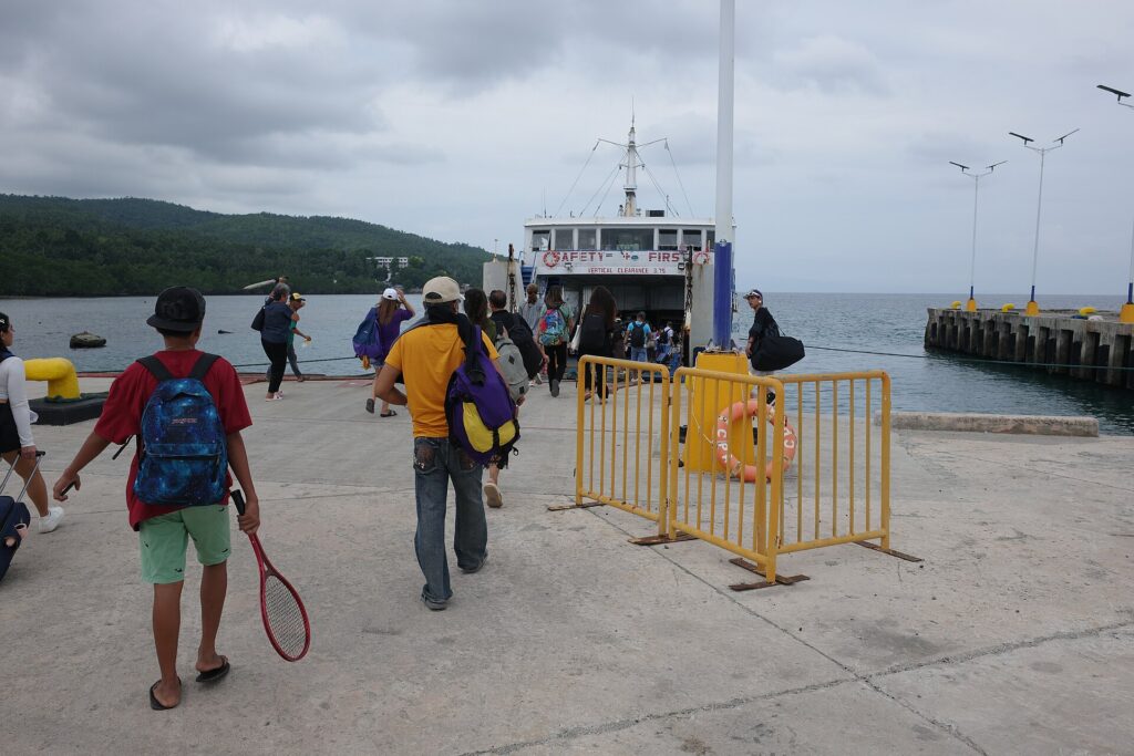 Passengers with backpacks walking toward a ferry docked at Poro Port in the Camotes Islands