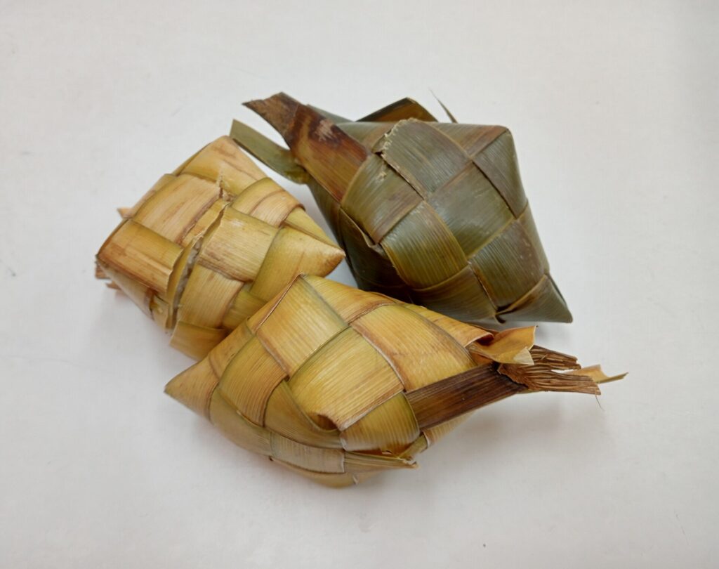 Three woven coconut-leaf pouches of puso rice, shown on a plain background