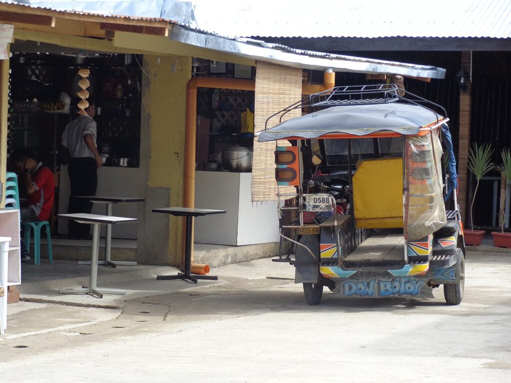 A motorcycle tricycle with a passenger sidecar parked outside a roadside eatery in Lapu-Lapu City