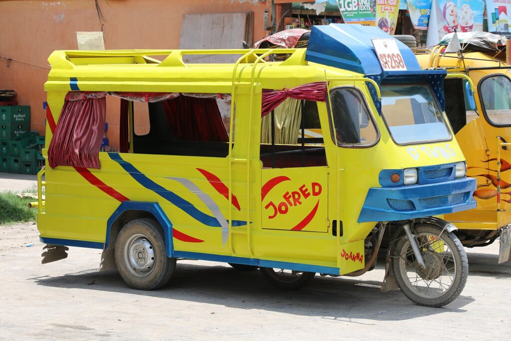 A yellow motorised tricycle with red curtains parked in a street on Bantayan Island