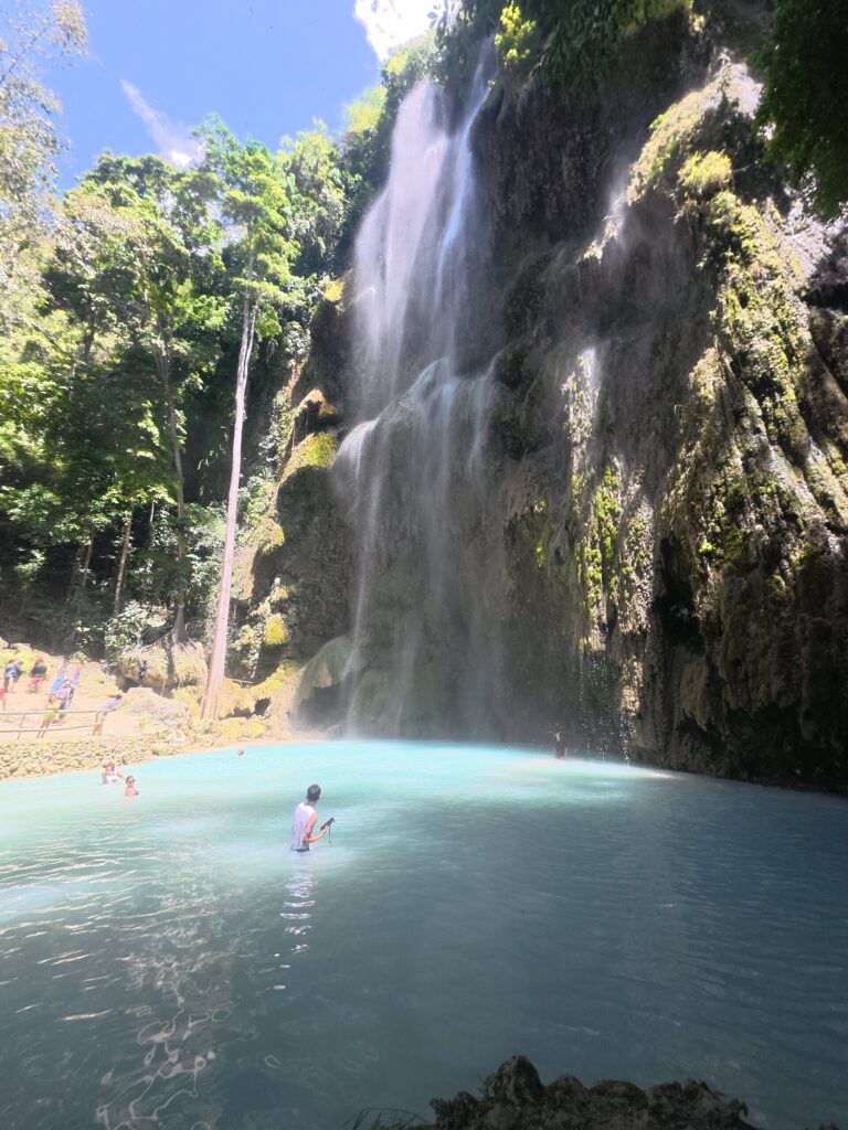 Full view of the falls above the pale blue pool