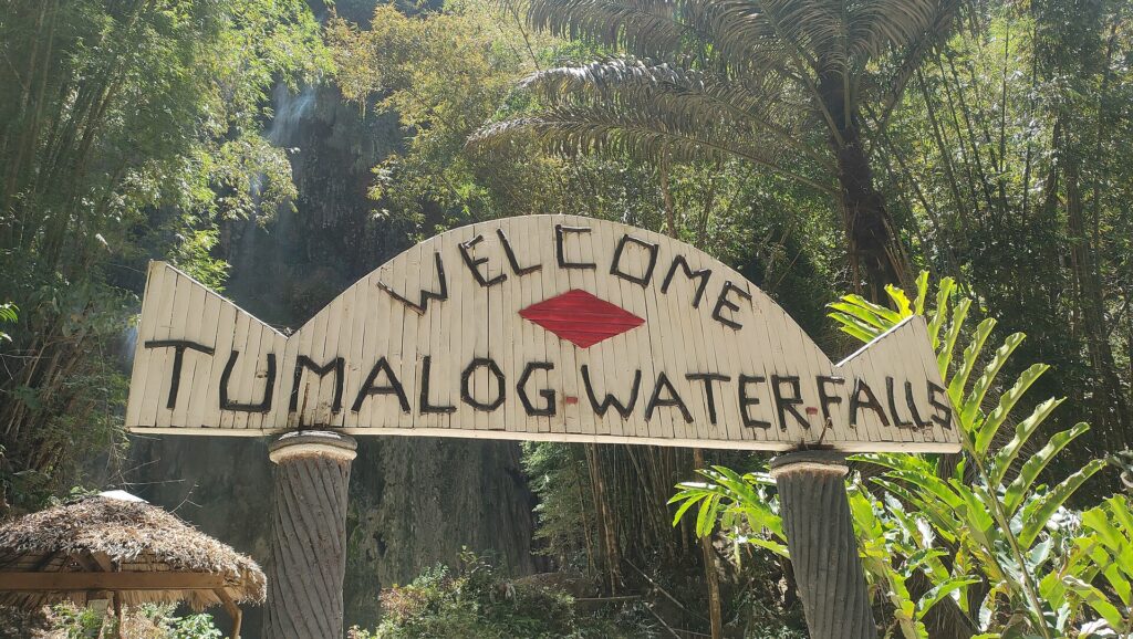 The wooden 'Welcome Tumalog Waterfalls' sign