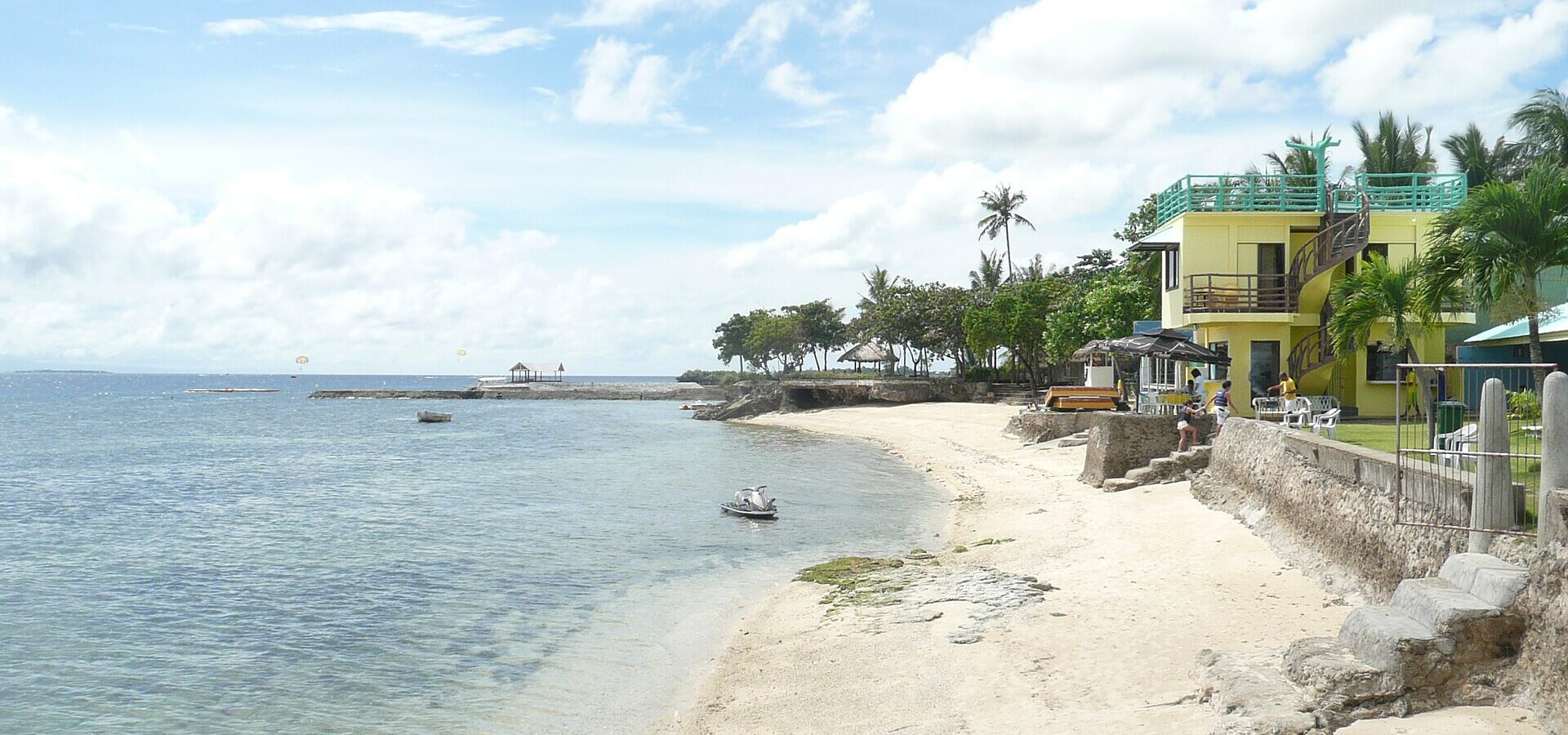A beach resort on Mactan Island with calm, clear water and palm trees